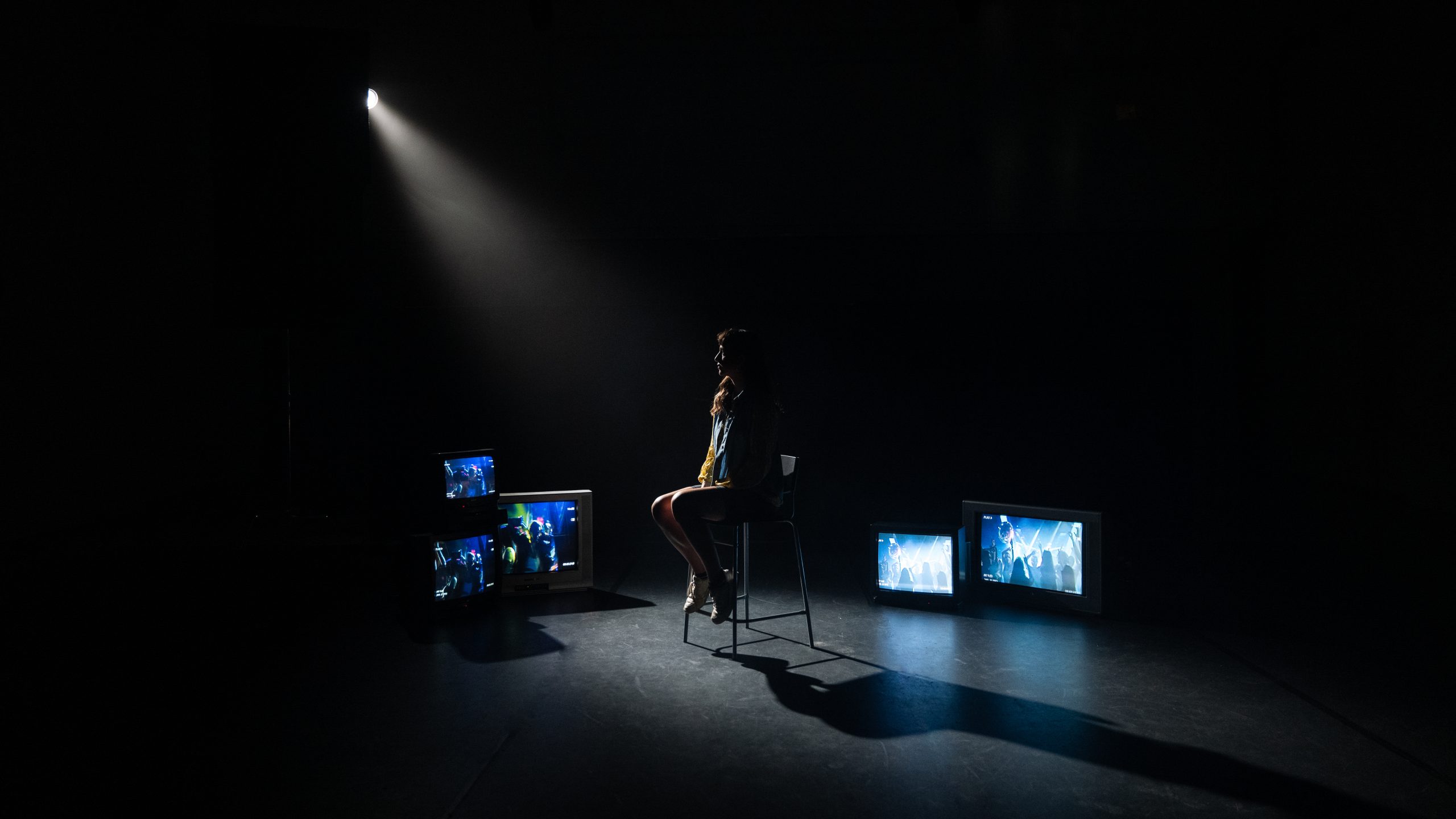 Frau sitzt in einem dunklen Raum mit Blick auf einen Bildschirm